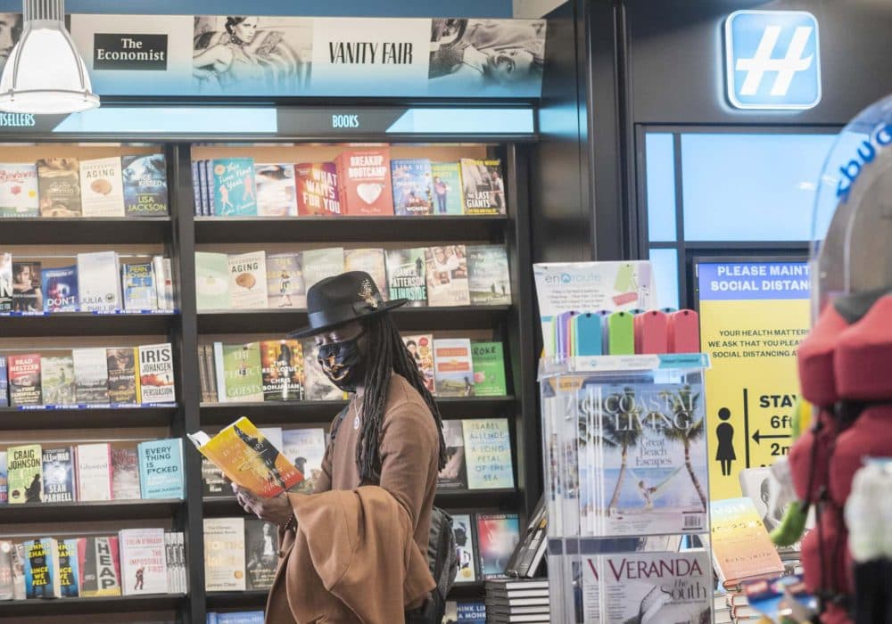 Man in hat reading at book in front of book display